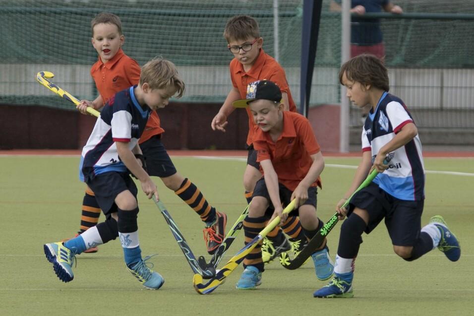 Gruppe von Kindern welche Hockey mit Schlägern spielen