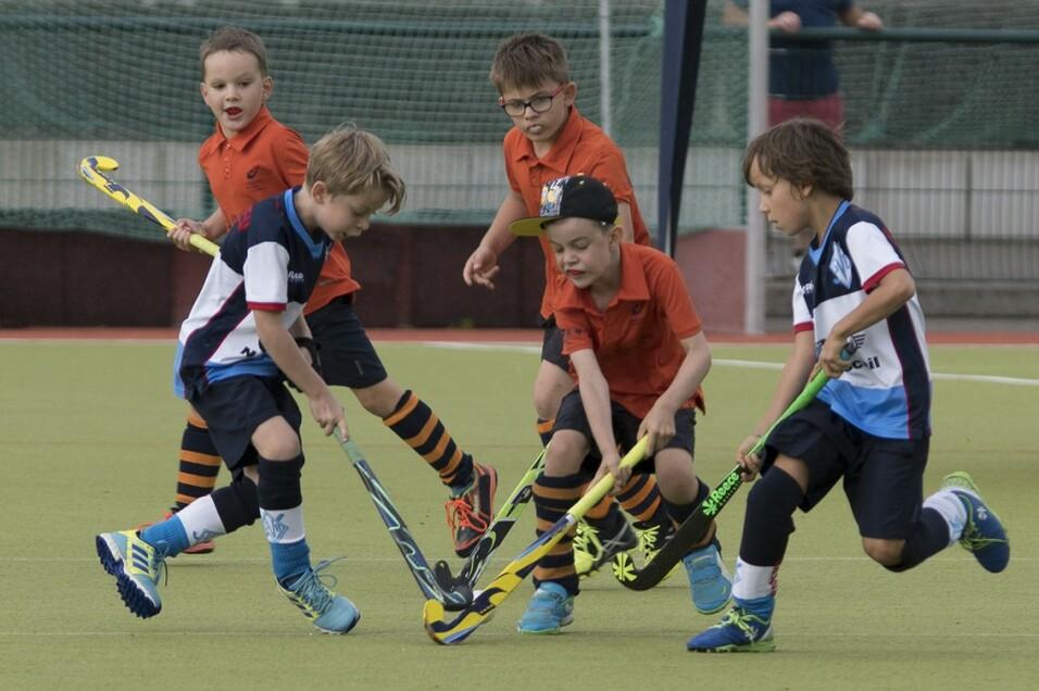 Gruppe von Kindern welche Hockey mit Schlägern spielen