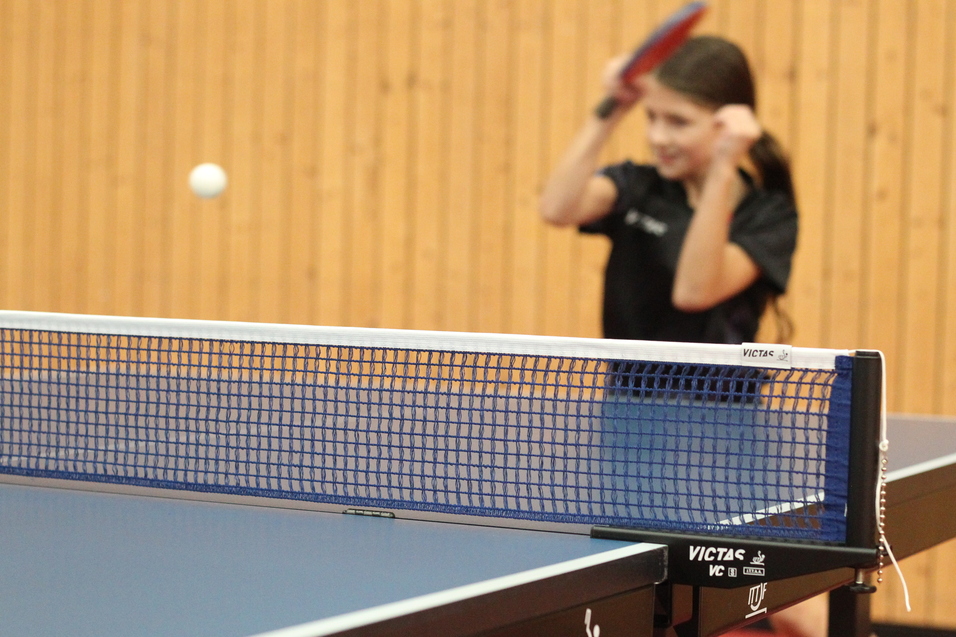 Spielerin schlägt Tischtennisball mit dem Schläger