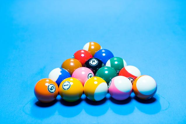 Ein Haufen bunten Billardkugeln in der Form eines Dreiecks auf einem blauen Billardtisch.