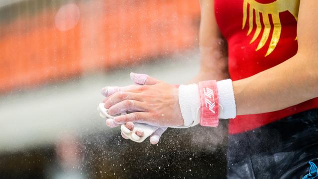 Nahaufnahme von Händen eines Turners mit Chalk, die vor einem Wettkampf im Gymnastik bereitgemacht werden.